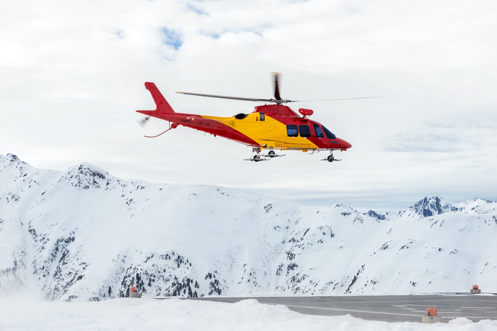 Mountain ski life rescue medic helicopter taking-off from station helipad to search injured skiers